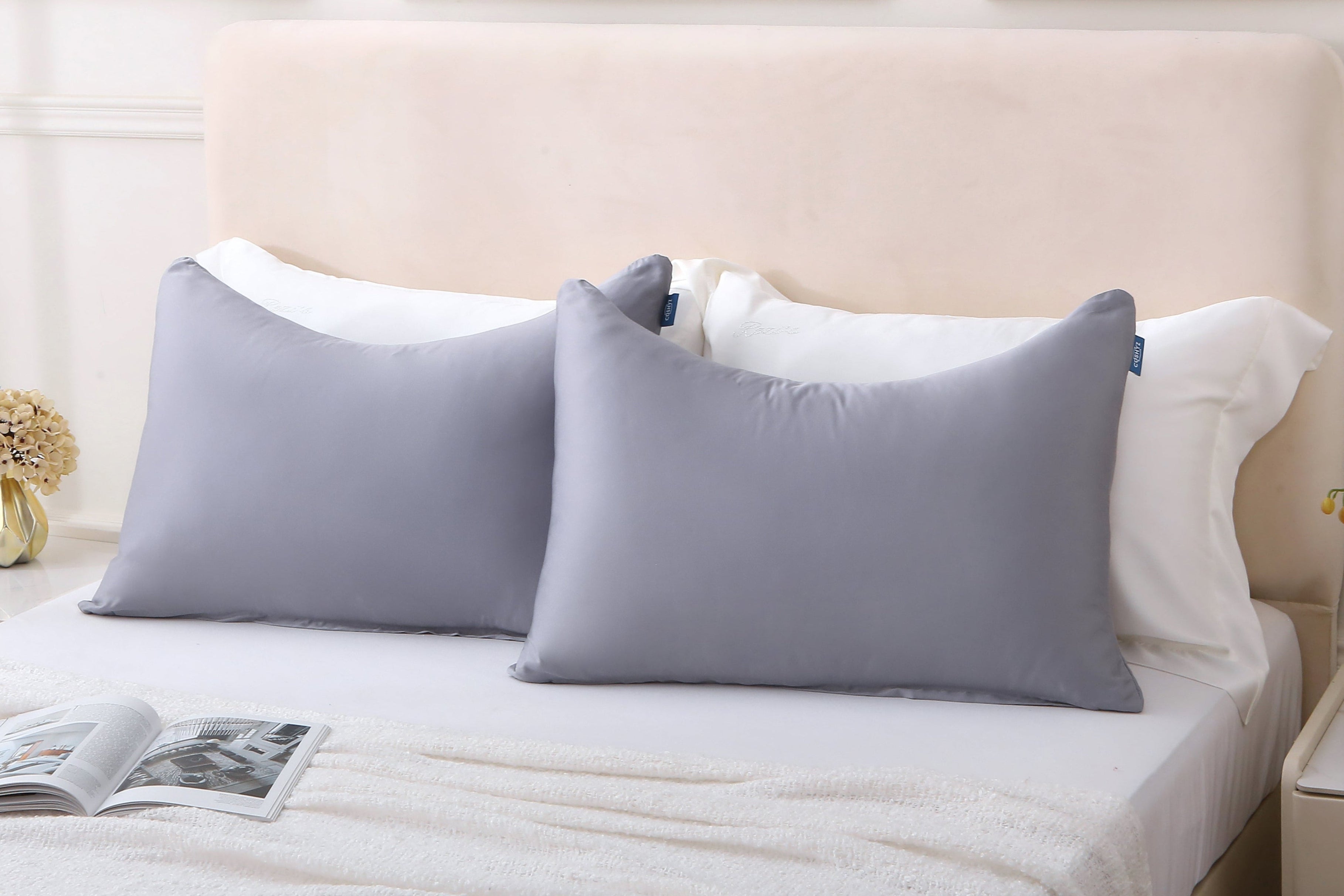 Cushyz bamboo cooling gray pillow covers are displayed on pillows neatly arranged on a bed with a neutral headboard and minimalist decor.