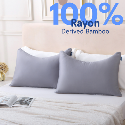 Two pillows in gray Cushyz curved bamboo cooling pillow covers are neatly placed on a bed, labeled 100% rayon derived from bamboo.